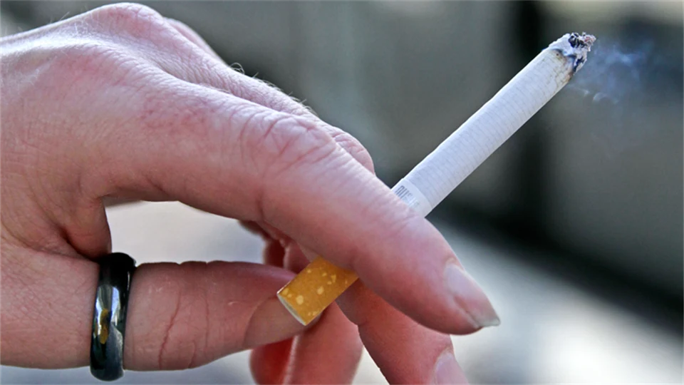 Hand som håller i en tänd cigarett.