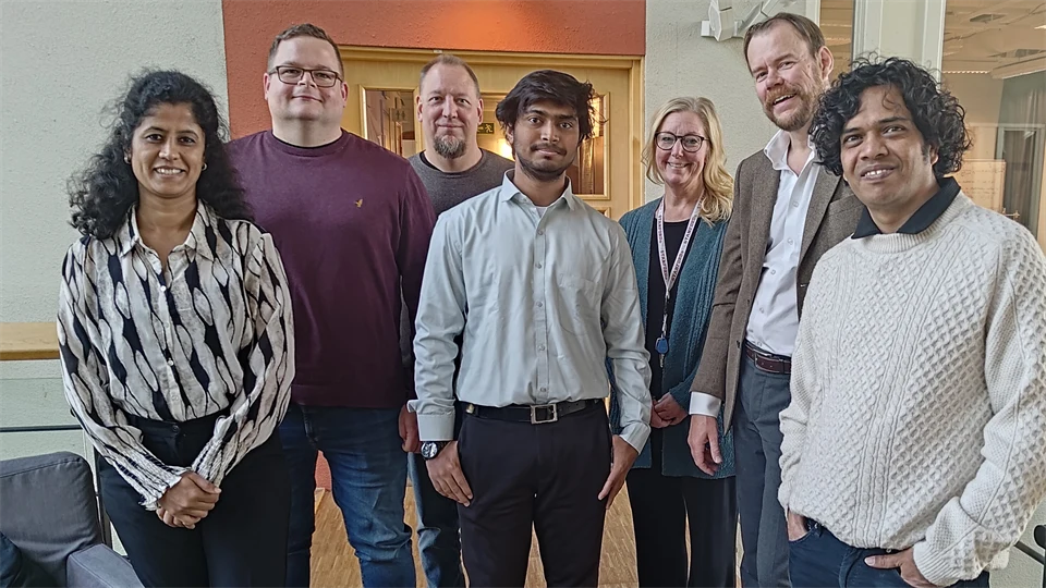A group of people stand together and look into the camera.