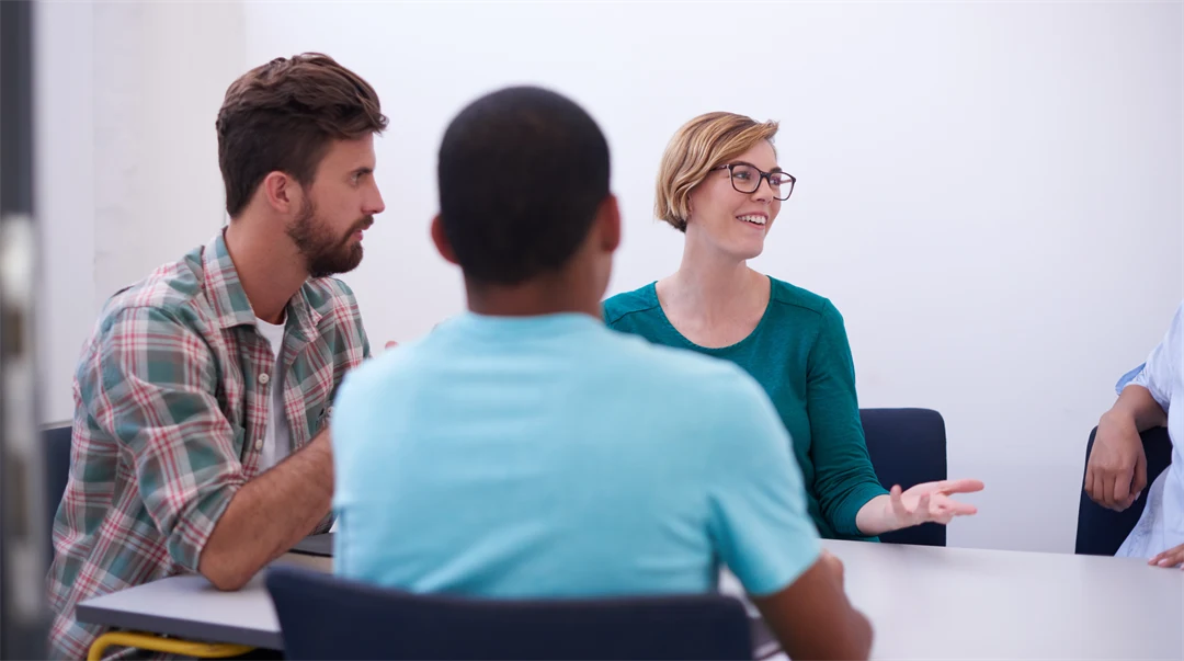 Tre personer, en kvinna och två män, sitter i ett informellt möte.