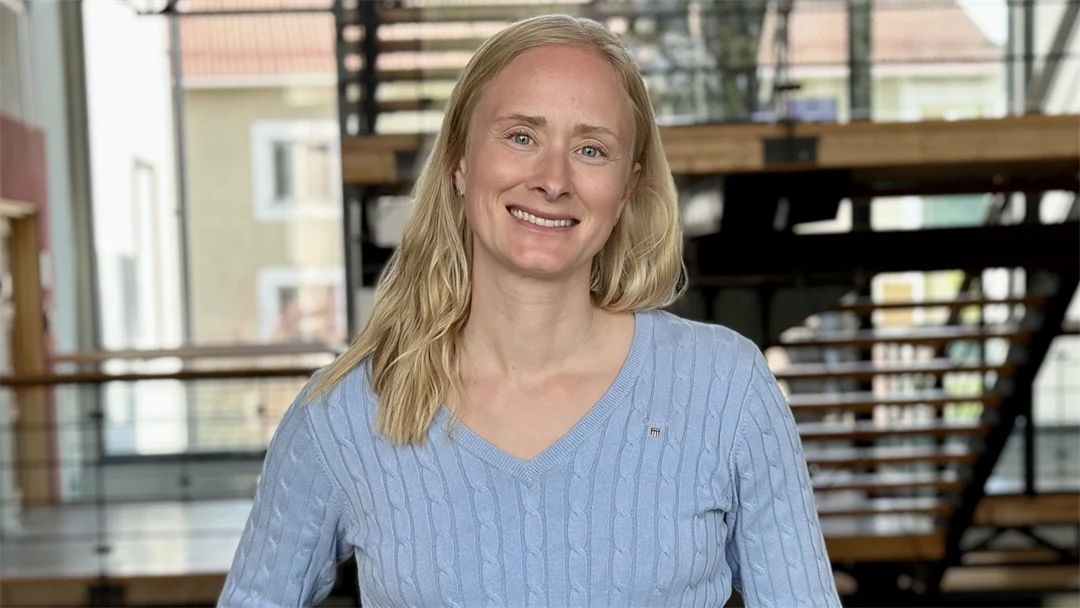 Amanda Mattsson, en kvinna i ljusblå tröja framför en trappa