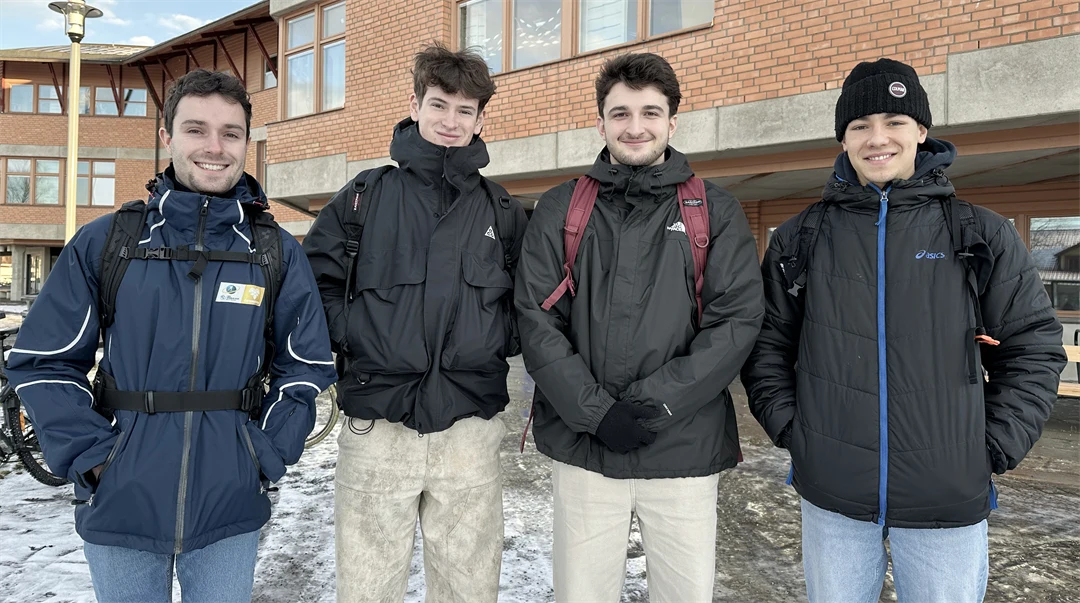 Fyra killar utomhus framför en tegelbyggnad.