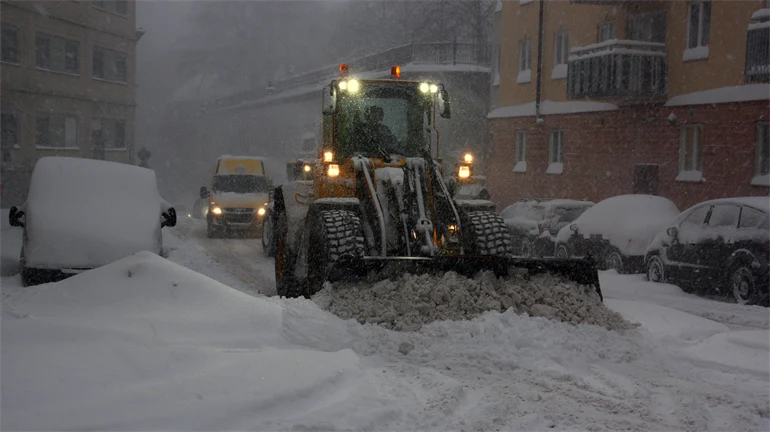 Traktor som skottar undan snö på gata.