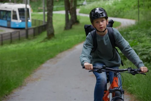 Ung cyklist, spårvagn i bakgrunden.