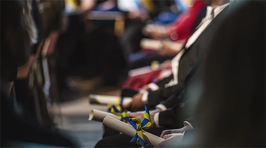 Well-dressed people sitting with diplomas in their hands. 