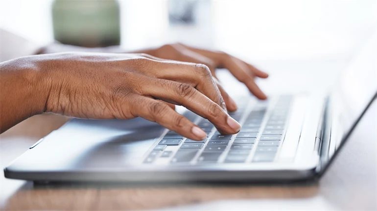 Två händer som skriver på en laptop