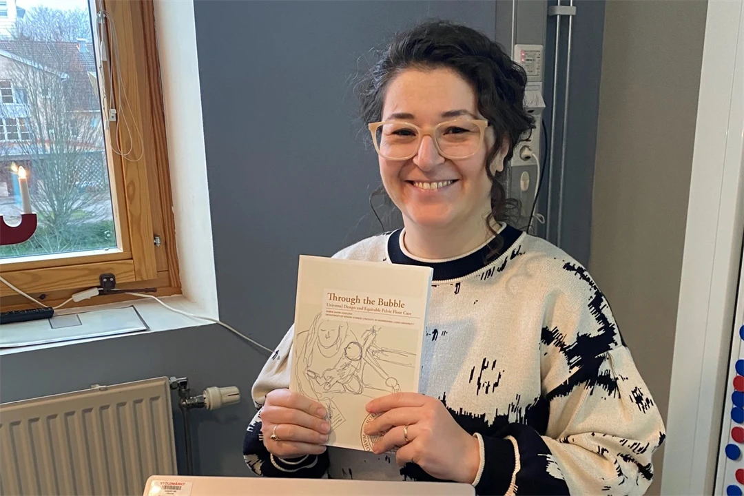 en kvinna ler och håller i ett häfte