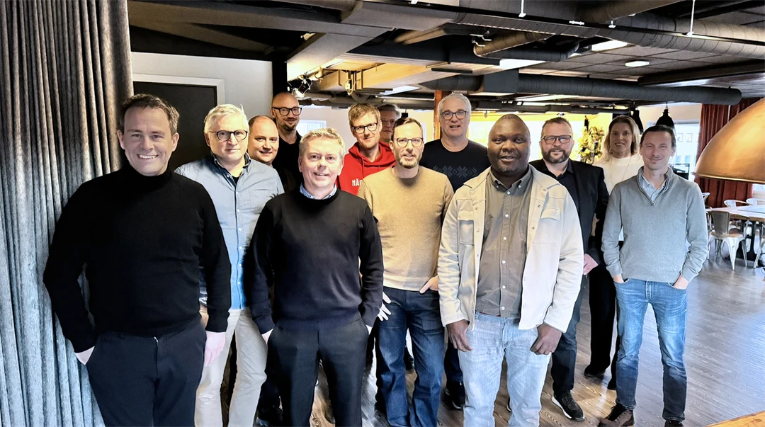 En grupp på 12 personer står mot kameran och ler