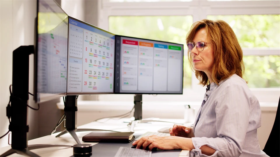 Kvinna som sitter och jobbar framför datorskärmar