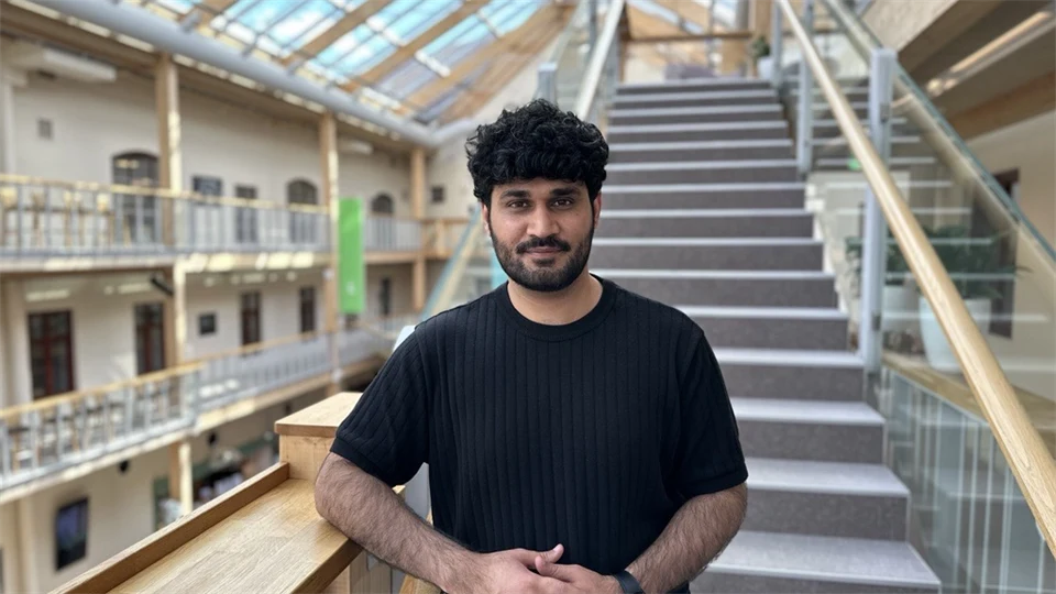A man with short black hair and a black t-shirt