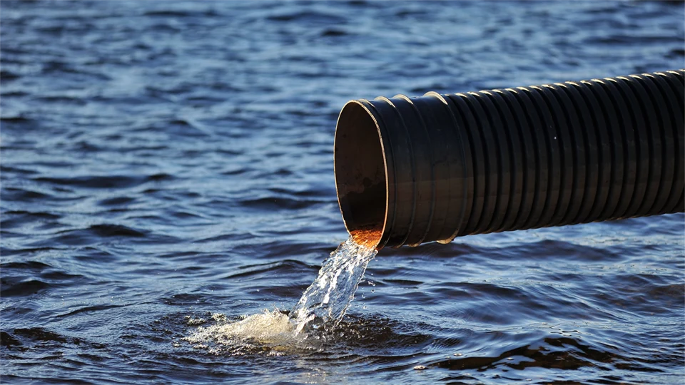 Water flowing out of a sewer pipe into a lake.