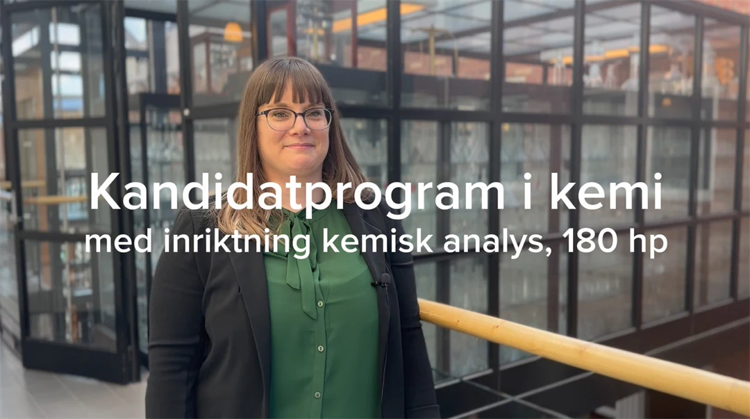 En kvinn ai mörkt hår och mörka kläder står framför en glasvägg