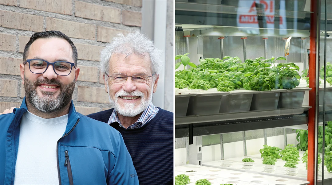 Två män som ler mot kameran. Gröna växter i ett glasskåp.