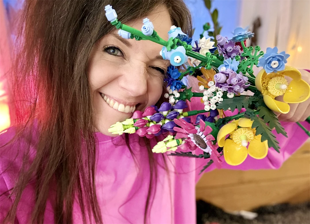 Bild på Samverkets community manager Sandra Olofsson i rosa tröja och en bukett legoblommor