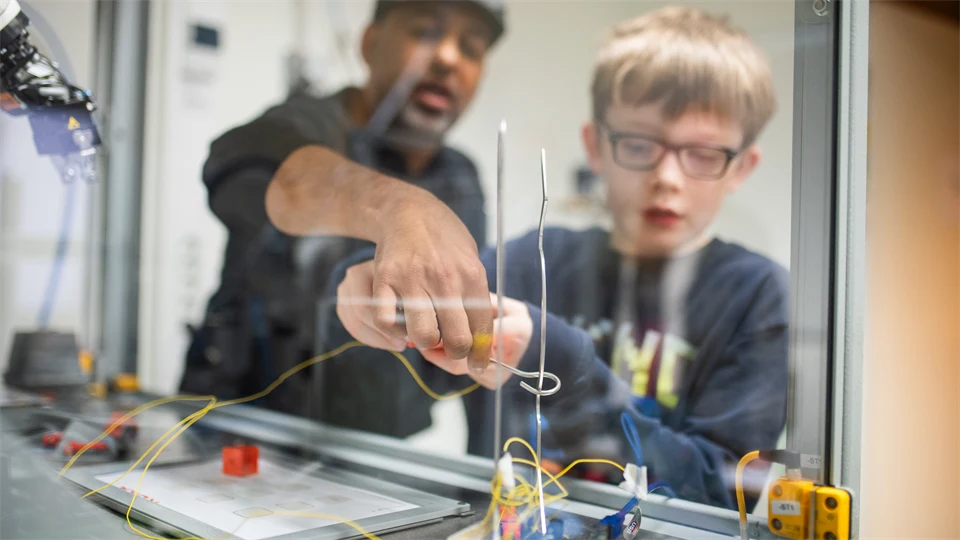 Researcher helps a kid in the lab.