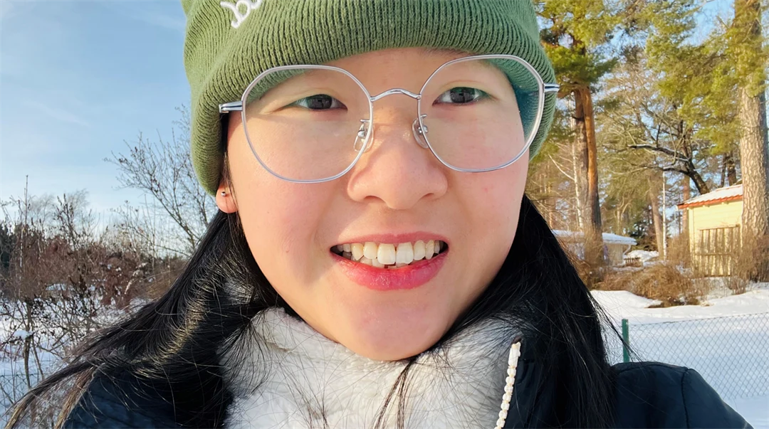 A woman in a winter landscape with trees and snow in the background.