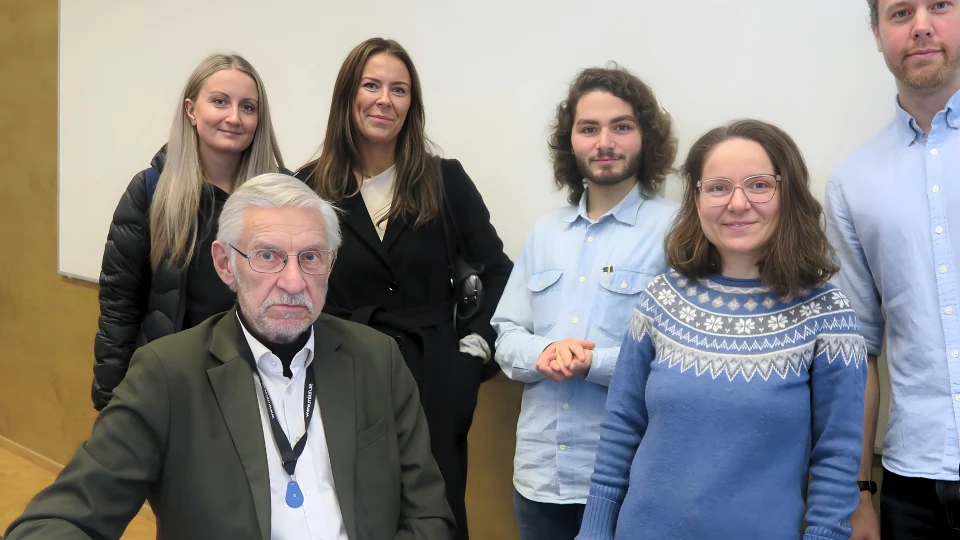 Manlig lärare i ett klassrum omgiven av fem studenter