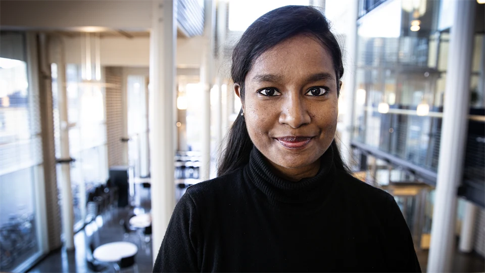 Woman in black shirt and with black hair looks at the camera.