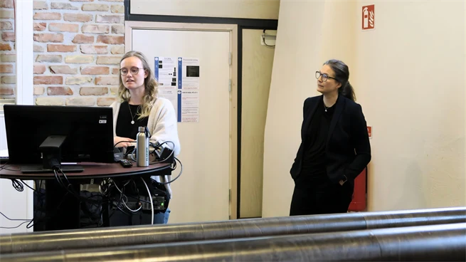 Två kvinnliga lärare står längst fram i en aula och pratar med åhörarna.