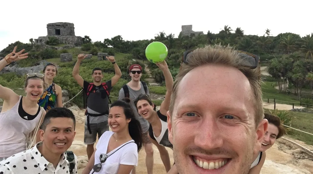 Axel Eriksson i förgrunden med en grupp glada människor bakom sig. I horisonten syns hus på en höjd.