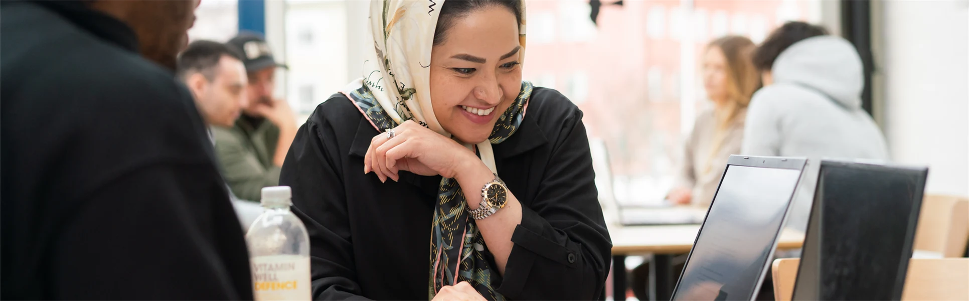 En kvinna sitter vid en dator och ler. 