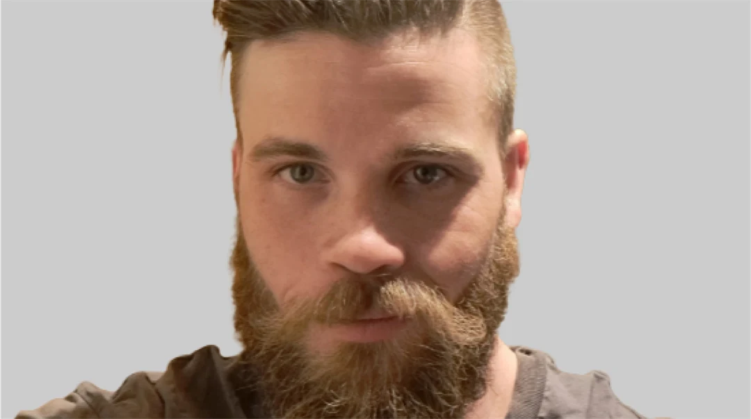 Selfie av ung manlig student från Förvaltningsjuridiska programmet. Han bär brun t-shirt, har helskägg och kort hår.