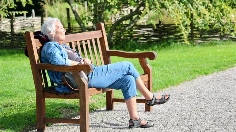 Äldre dam på parkbänk