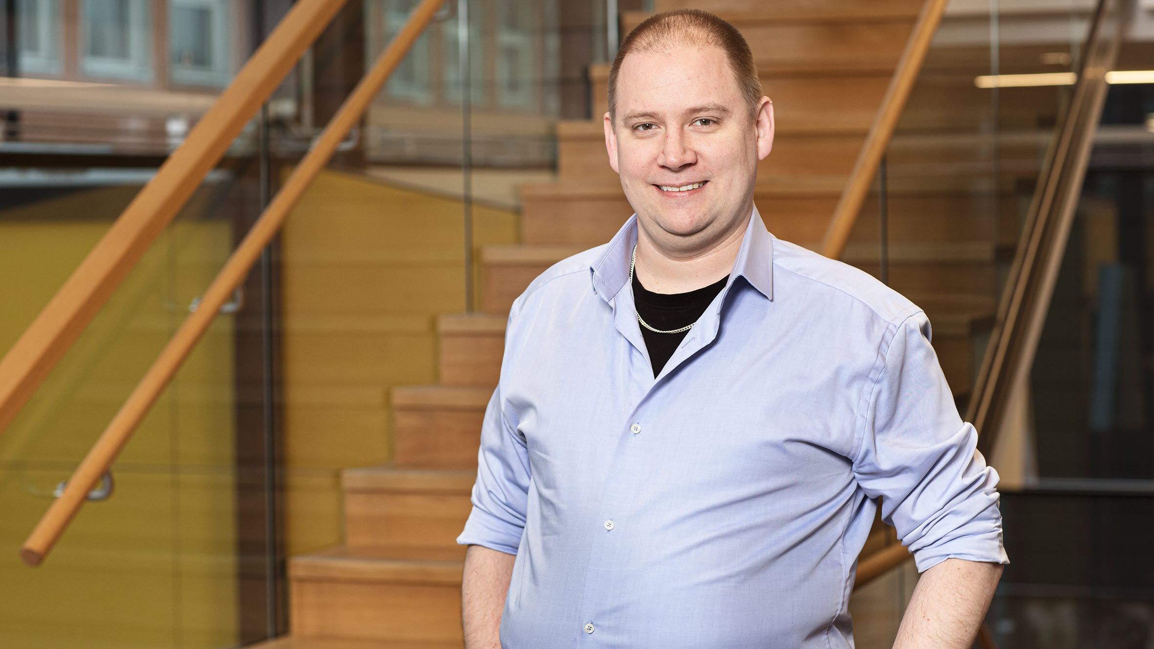 En man med ljusblå skjorta och kort hår poserar framför kameran.