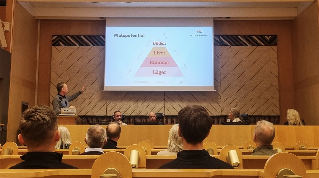 Människor sittandes i en föreläsningssal, lyssnandes till en föreläsare