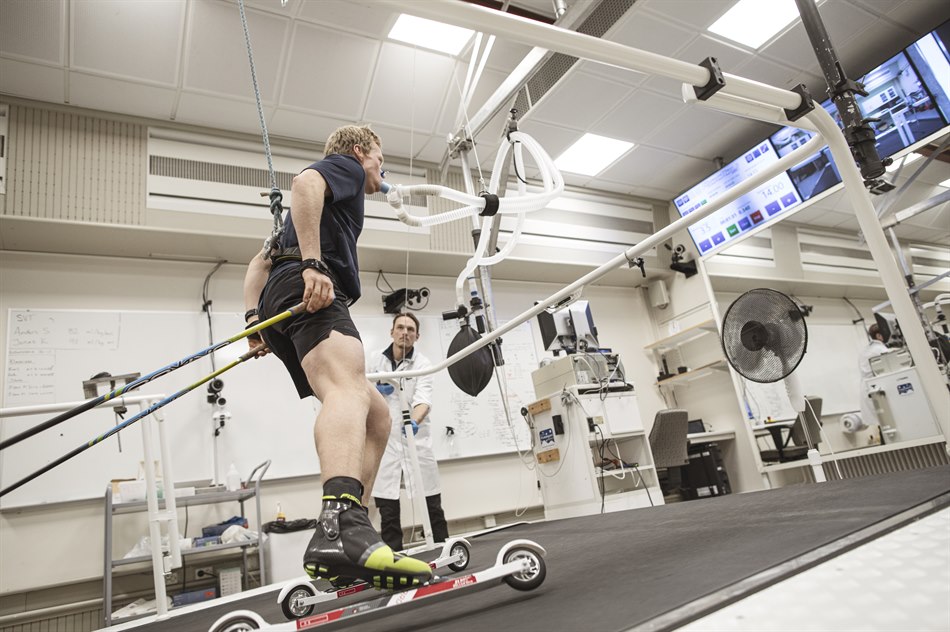 Alfred Buskqvist åker rullskidor på rullband med testutrustning som mäter syreupptagning, övervakas av testledare Hampus Lindblom.