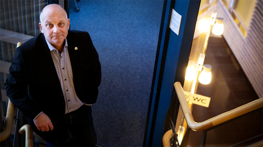 En man står avslappnad och tittar upp mot kameran.