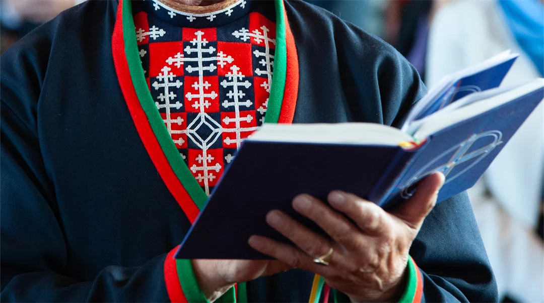 Man med sydsamisk kolt och barmkläde läser i den sydsamiska bibeln.