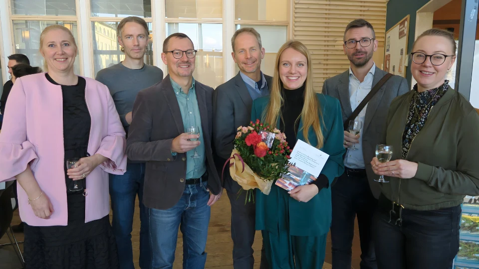 Sex forskare tillsammans med doktorand som håller blommor