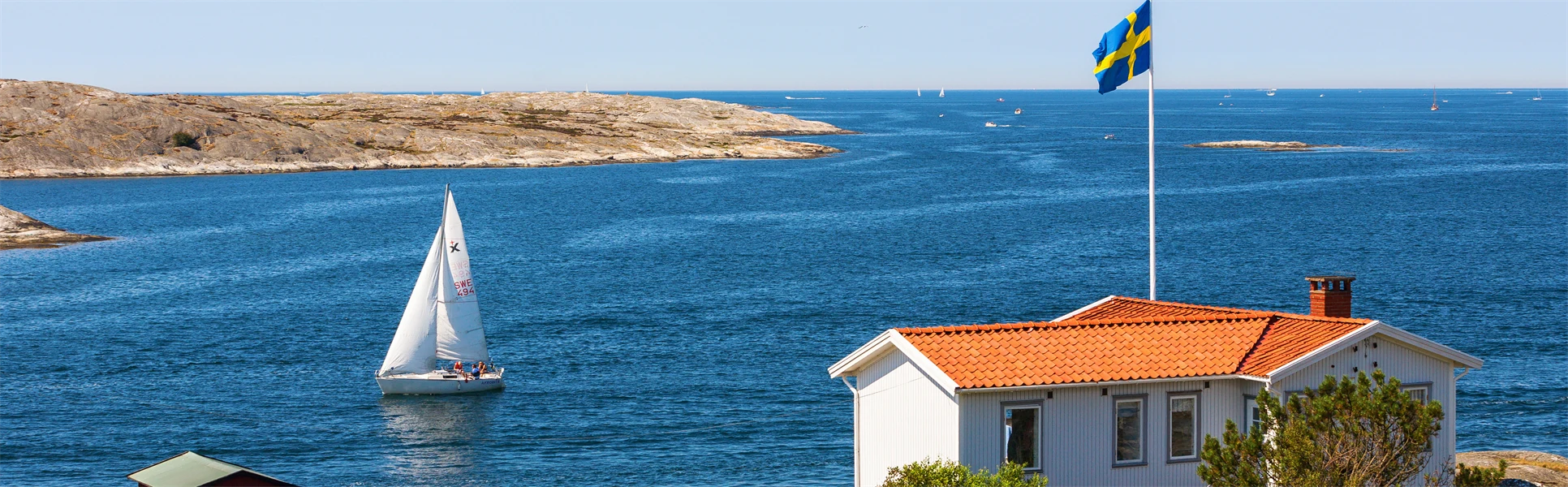 En vy från en skärgård i Sverige med en stuga och svenska flaggan