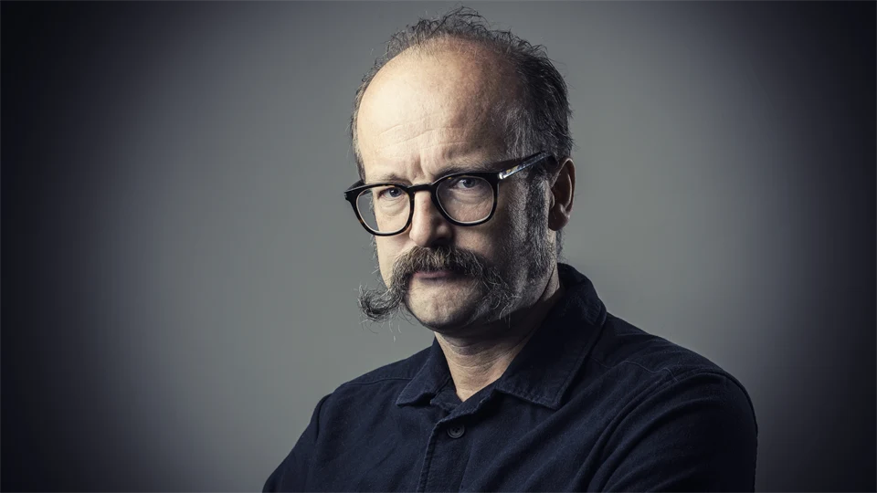 POrträttfoto av en man med svart skjorta och svarta glasögon