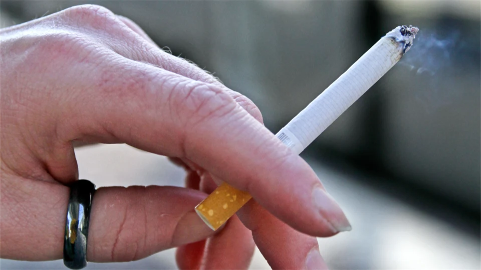 Hand holding a lit cigarette.