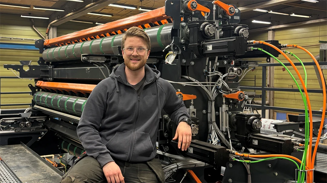 En man sitter framför en industrimaskin.