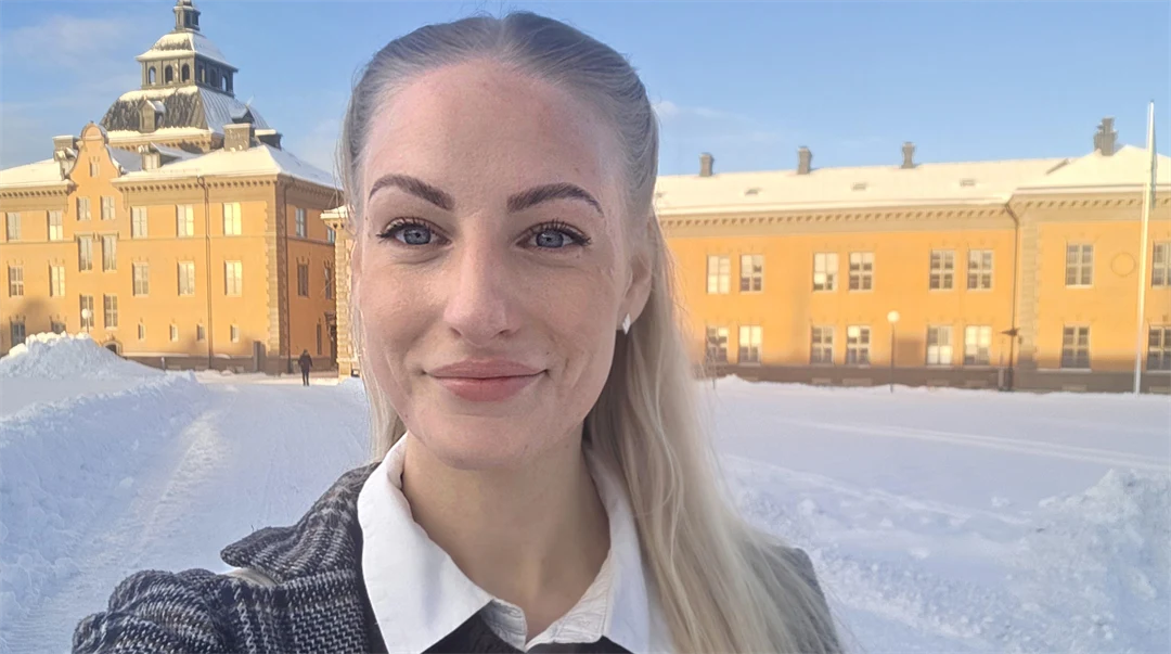 Utomhusbild av kvinna som står med byggnad i bakgrunden.