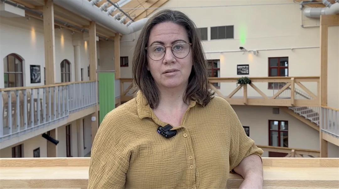 En kvinna i senapsgul blus, mörkbrunt hår och glasögon.