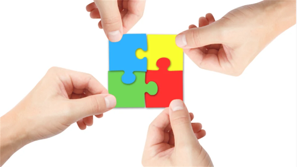 Fyra händer som håller i var sin färgglad pusselbit till ett helt pussel.