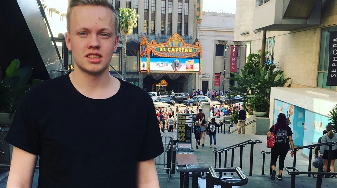 Kille i svart t-shirt står på en gata i Iowa, i bakgrunden syns byggnader och människor