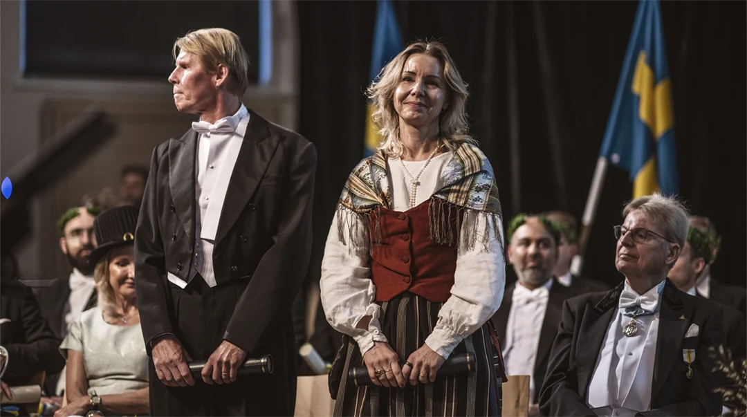 En finklädd man och en finklädd kvinna står bredvid varandra på en scen. 