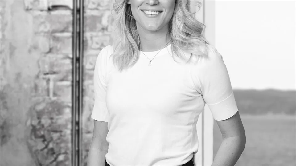 Kvinna med ena handen i fickan som står framför en tegelvägg