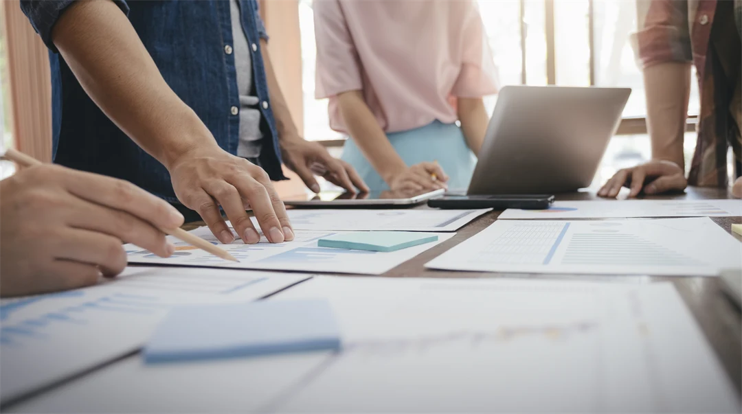 Table with papers and people holding out their hands