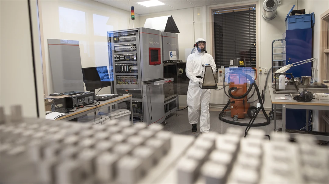 En person i vit skyddsdräkt går i ett labb.