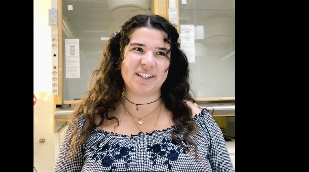 Ung kvinna i rutig blus och mörkbrunt hår. 