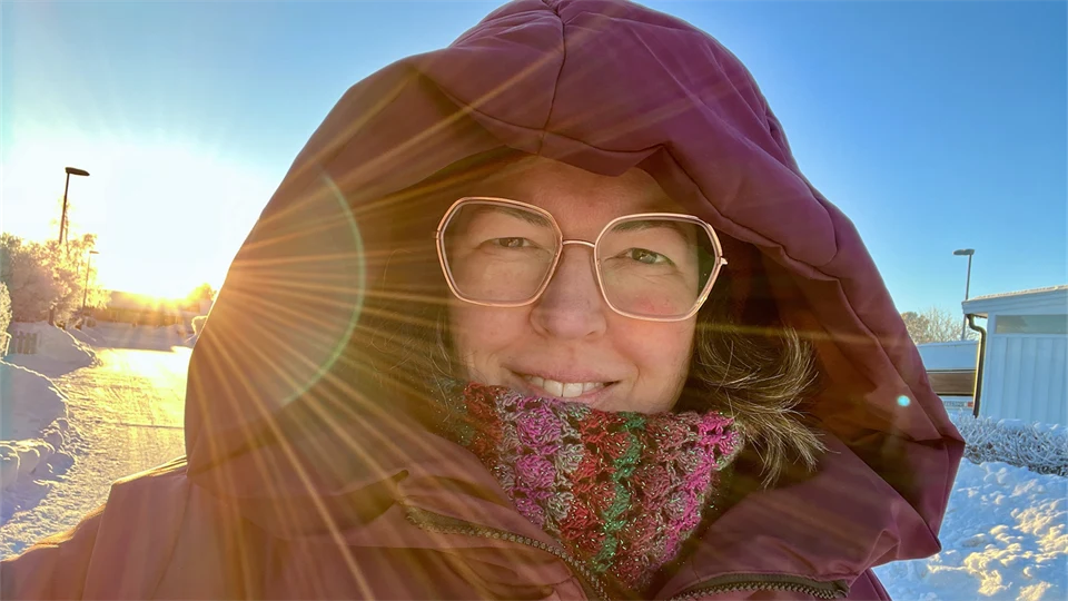 En kvinna i stor lila vinterjacka och glasögon.