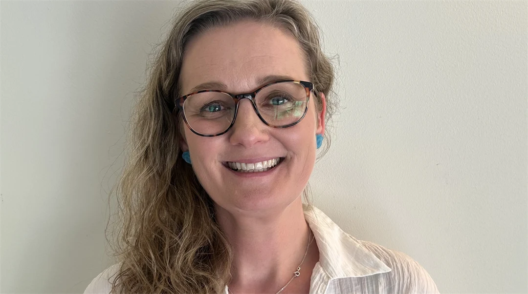 A portrait photo of a woman with blonde hair and a white shirt