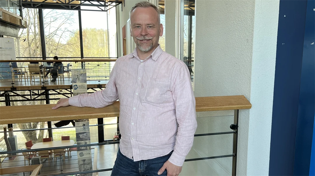 En man i en ljus skjorta står i en ljusgård.