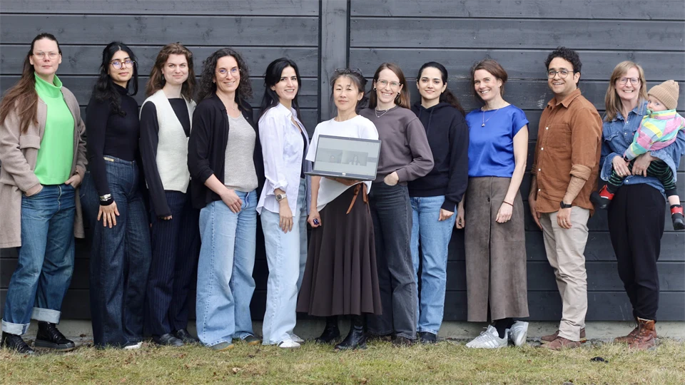 Grupp kvinnor står uppradade framför en mörk vägg