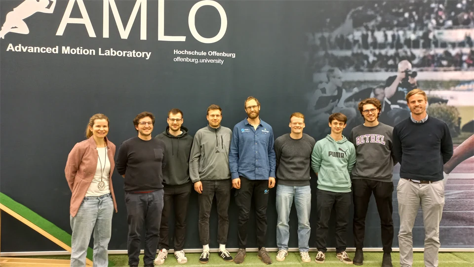 Nio personer som står framför en vägg.